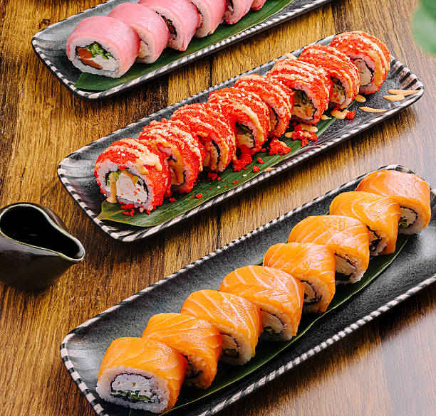 istock Sushi platters with assorted rolls displayed on wooden table 2229683475