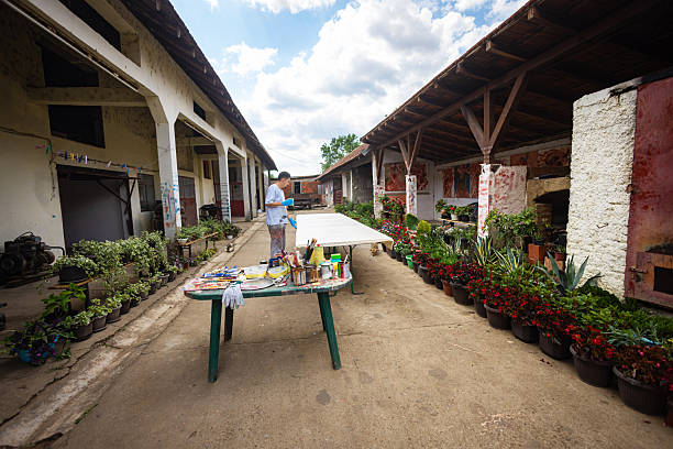 A handcrafted wooden table and stools sit beneath a red-tiled shelter, offering a peaceful and poetic corner surrounded by nature. This artistic image captures the quiet charm of rural simplicity, emphasizing natural textures, earthy tones, and a tranquil atmosphere—ideal for lifestyle editorials, design inspiration, or visual storytelling.