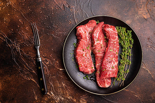 istock Tri tip steaks, Raw marbled beef meat on plate with herbs. brown background. top view 2229684056