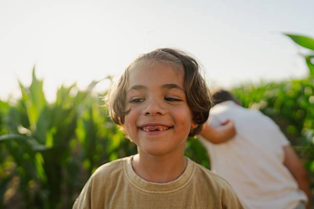 Photo of a cheerful young boy, posing for a portrait in a corn field