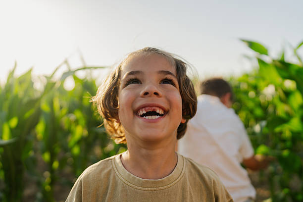 Photo of a cheerful young boy, posing for a portrait in a corn field