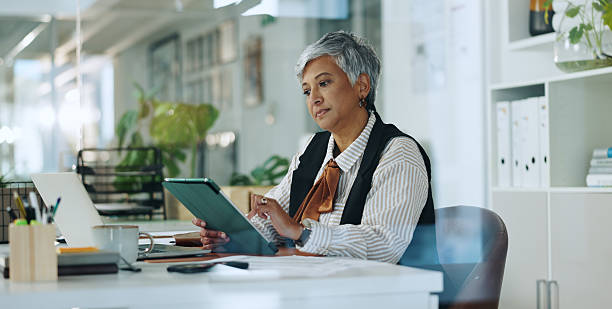 istock Creative, mature woman and tablet in office for editor feedback, information and article post. Female journalist, digital and proofreading of latest news, update draft and review story of publication 2229696701