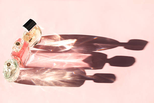 istock Beautiful perfume bottles casting shadows on light pink background, above view 2229712066