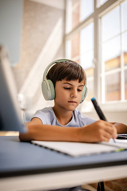 istock Young boy focused on drawing while wearing headphones indoors in a modern home setup 2229718524
