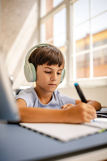 istock Young boy engaged in creative drawing while listening to music at home in a bright, inviting room 2229718541
