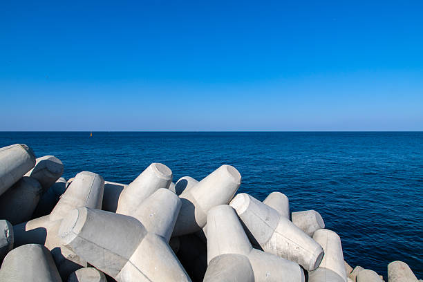 Beautiful sunset seascape. Breakwaters tetrapods ashore of pier. Cargo ships on the horizon. Travel dreams and motivation