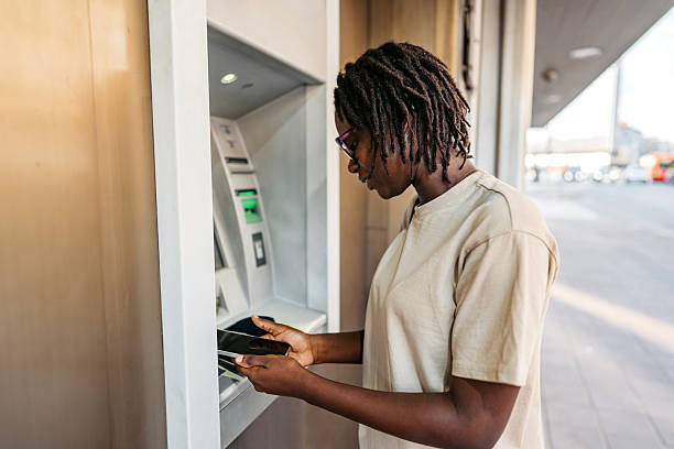 istock Young Black Woman Withdrawing Money Using A Phone At The ATM Machine 2229721696