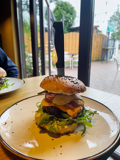 istock Grilled beef burger with lettuce, cheese and cucumber on plate in pub. Cheeseburger, hamburger on plate. 2229723115