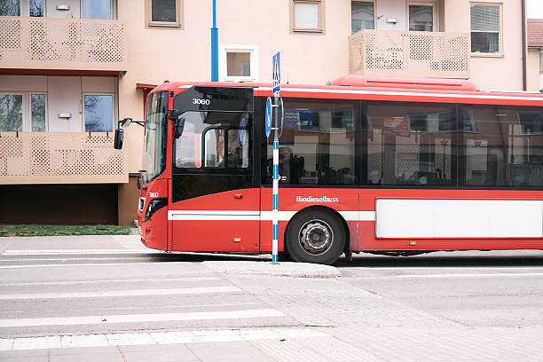 Nynashamn, Stockholm County, Sweden - April 17, 2025: A red bus is driving down a street. The bus is passing a crosswalk