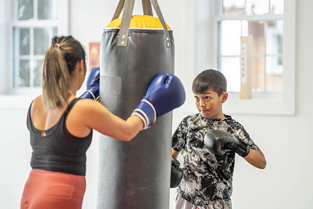 istock Mother and Son Training Together Using a Punching Bag in a Gym 2229726937