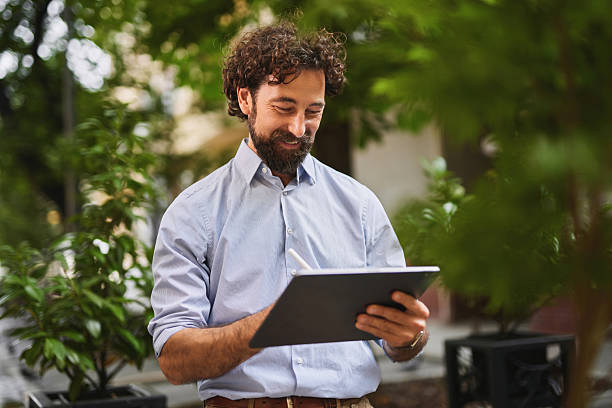 istock Smiling businessman working on digital tablet outdoors 2229732035