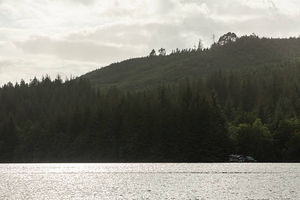 A lake with a boat on it and a mountain in the background. The sky is cloudy and the water is calm