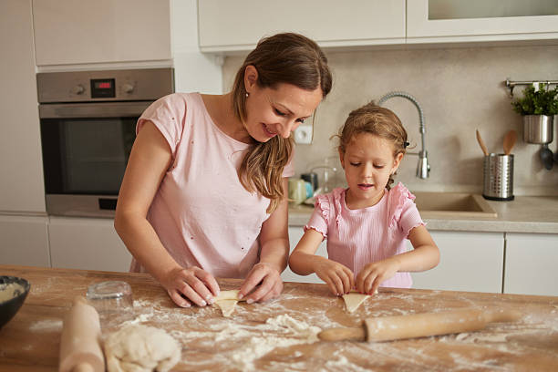 istock Mother and daughter making dough pastry in kitchen 2229739017