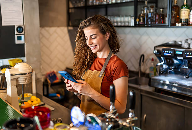 istock Smiling barista using smartphone behind counter in cafe 2229739851