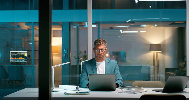 istock Mature man, typing and laptop in office at night for research, editing article and feedback report. Journalist, PC and draft of story update, review newsletter and information on publication deadline 2229742523