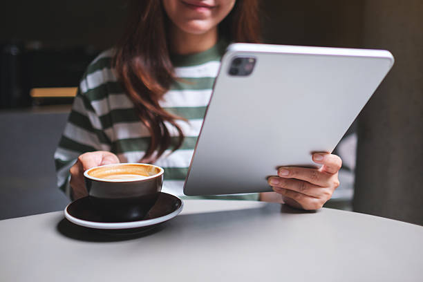 istock Closeup of a woman holding and using digital tablet while drinking coffee in cafe 2229742922