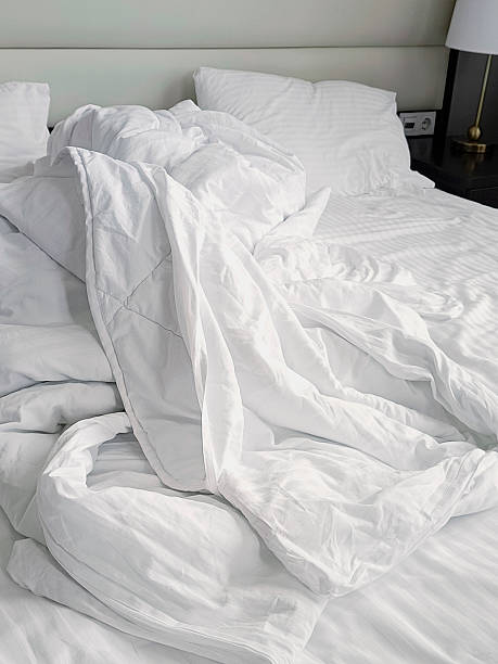 istock Crumpled white bed linen on a bed. Unmade bed. Close-up, vertical photo. 2229744058