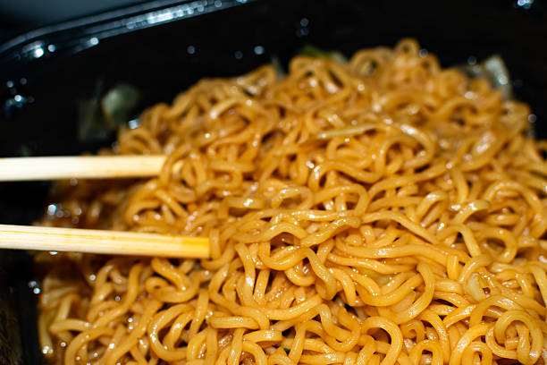 Close up of Asian cuisine noodles and chopsticks. The noodles are flavored with teriyaki and soy sauce.