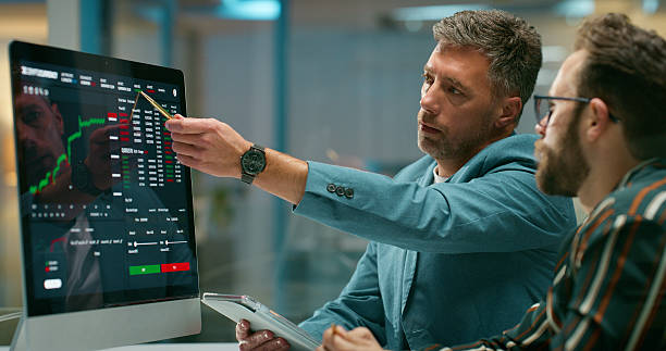 istock Computer screen, coaching and stock market with business people in office for trading, data and night. Research, investment planning and overtime with employees in broker agency for coworking 2229745647