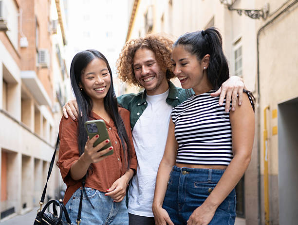 istock Group of young adults sharing a laugh while using a smartphone in the city 2229747889