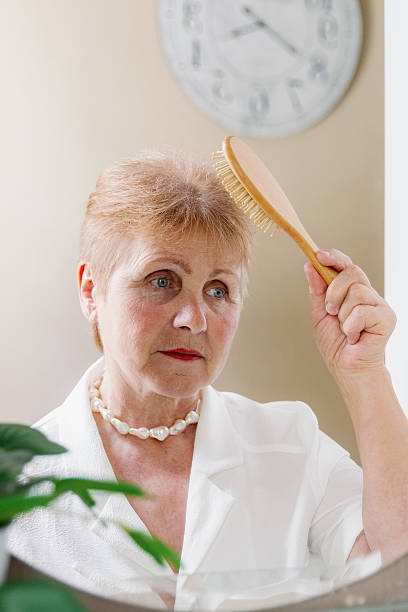 istock One elderly stylish woman combs her hair while looking in the mirror. 2229748811