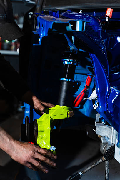 istock Installing rear suspension arms under the chassis. Rear Suspension Installation Under Chassis for Drift Car Build. Technician tightens arms and subframe connections beneath the chassis. 2229749649