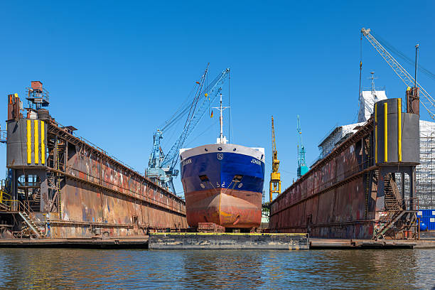 Hamburg, Germany - July 1, 2025: A large ship named Johann in a dry dock in Hamburg surrounded by industrial cranes and machinery under a clear blue sky.