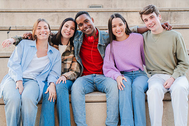 istock Joyful Group of Five Diverse Friends Enjoying Time Together While Sitting on Steps in a Relaxed Pose with Smiles and Laughter Captured in a Heartwarming Moment of Friendship and Togetherness 2229755310