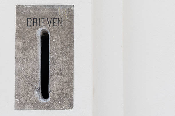istock Vintage mail slot embedded in a textured concrete wall, featuring a narrow opening for letters, surrounded by a clean white background, evoking a sense of nostalgia and communication history 2229756657