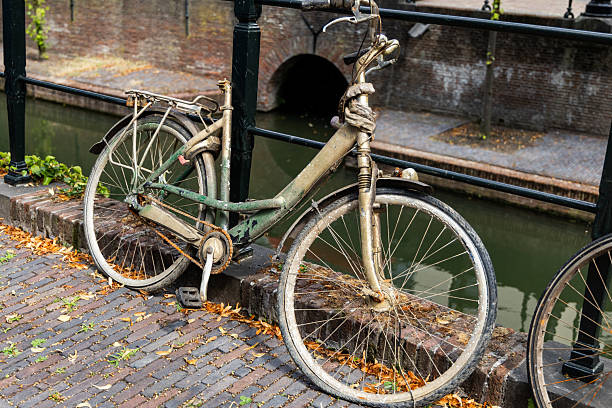 Bicycle retrieved from water canal, showcasing weathered details and rustic charm, surrounded by cobblestone path and serene waterway ambiance