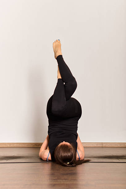 istock Woman practicing shoulder stand yoga pose in bright studio 2229757120