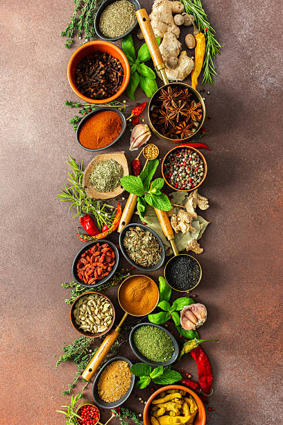 An artistic display of fragrant herbs and spices, scattered on a brown surface, blending natural hues and rich textures for a rustic culinary charm
