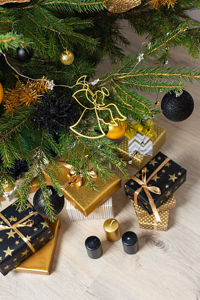 istock A festive scene featuring gold and black gift boxes, surrounded by shimmering candlelight and stylish decorations under a beautifully decorated Christmas tree, exuding elegance and charm 2229757881