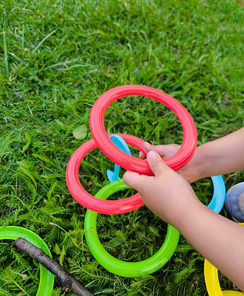 istock Children's hands playing with colorful plastic rings on green grass 2229760401