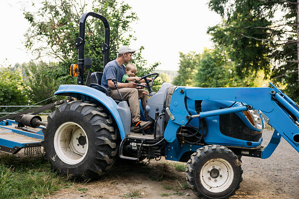 istock Farmer Drives Tractor With His Son Assisting 2229761019