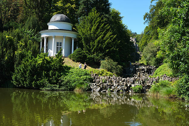 A tranquil and peaceful garden featuring an elegant gazebo and a serene lake, all embraced by lush greenery