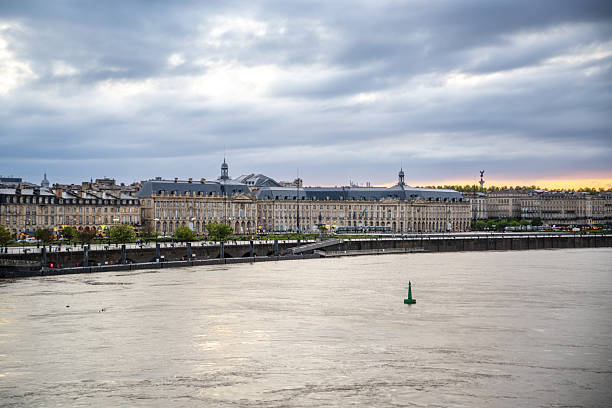 Scenic view of Bordeaux's iconic architecture along the Garonne River under a dynamic evening sky.