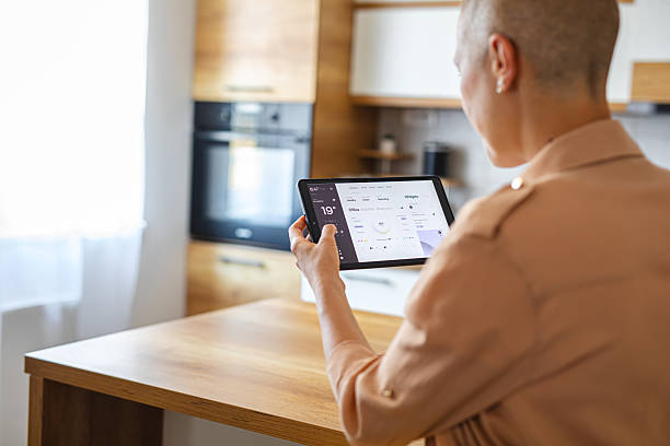 istock Woman using a touchscreen device to manage smart home functions from the comfort of the kitchen 2229763814