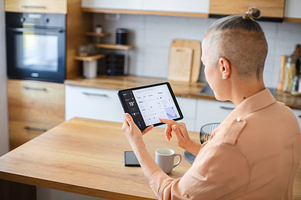istock Woman using a touchscreen device to manage smart home functions from the comfort of the kitchen 2229763833