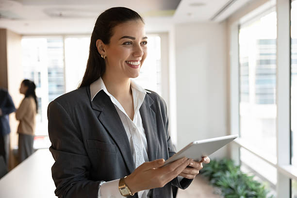 istock Portrait smiling young woman standing in workplace holding digital tablet 2229763989