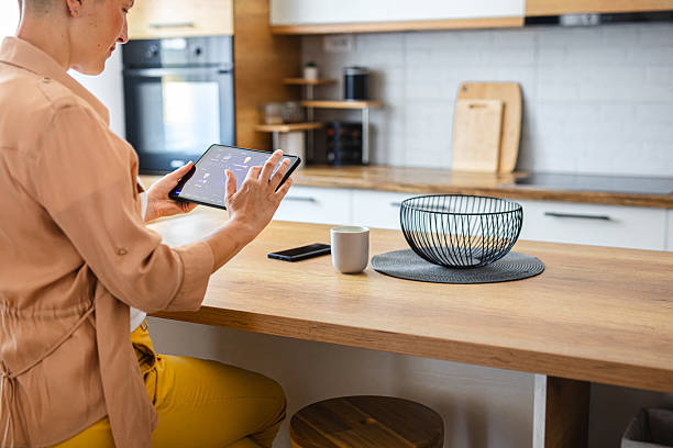 istock Woman using a touchscreen device to manage smart home functions from the comfort of the kitchen 2229764022