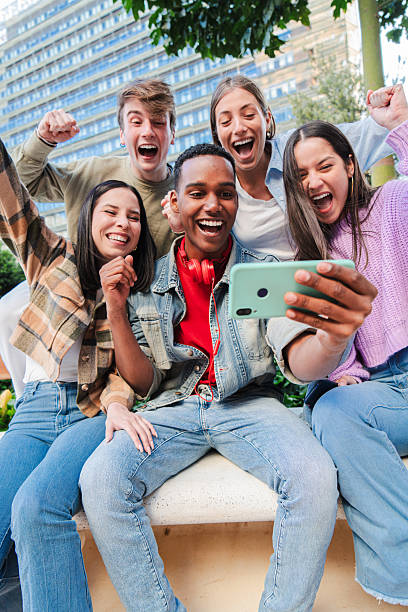 istock Vertical Group of young teenage students looking at their notes using a cellphone and celebrating joyfully having passed. Successful friends excited cheering with a smartphone. Classmates goals 2229764341