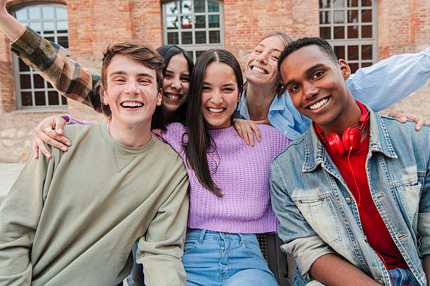 istock Joyful group of five young friends smiling brightly while posing together for a fun photo, showcasing their happiness and connection in a lively gathering filled with laughter and excitement 2229764731