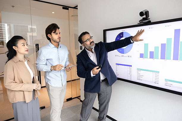istock Mature businessman mentor teach diverse young interns at digital board 2229768944