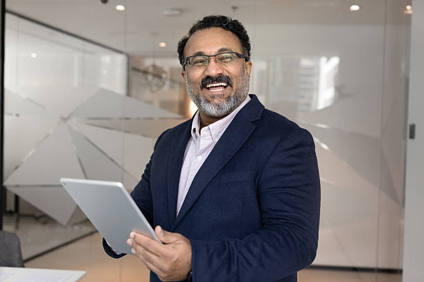 istock Happy mid aged businessman distracted from using tablet in office 2229769137