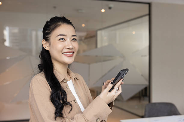istock Beautiful female office worker using mobile phone app in office 2229770838