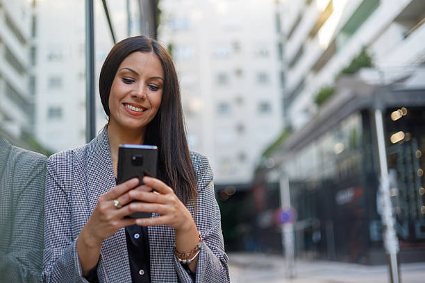 istock Confident professional checking smartphone, networking outdoors with urban skyline in background 2229772768