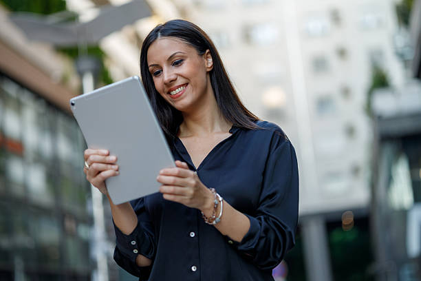 istock Businesswoman is smiling while using a digital tablet in an urban setting, likely for work or communication purposes 2229773516