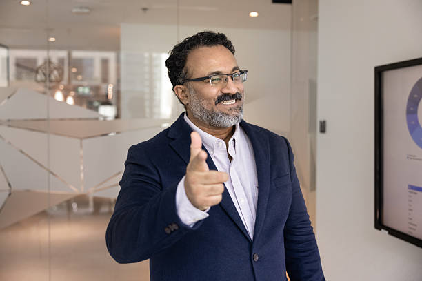 istock Smiling mature businessman looking at camera pointing finger at you 2229776436