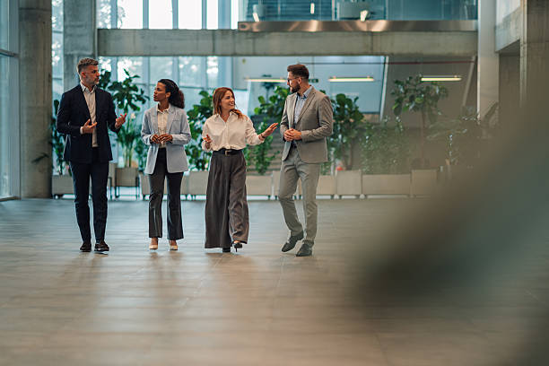 istock Businesspeople walking and talking in modern office building lobby 2229783739